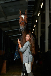 Side view of young woman standing in stable