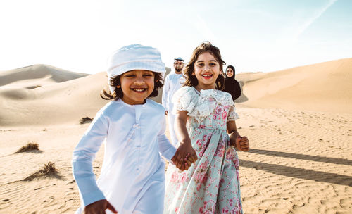 Portrait of happy friends standing on sand