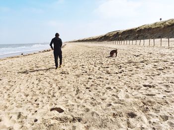 Rear view of men walking on beach