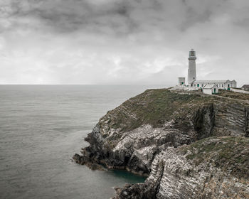 Lighthouse by sea against sky