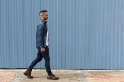 Portrait of a young man walking over blue background