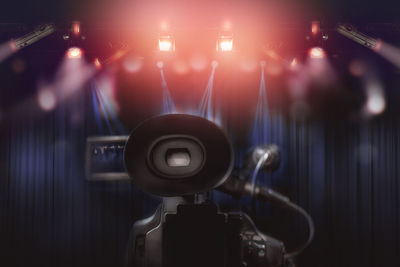 Close-up of television camera against illuminated stage