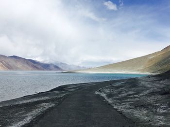 Scenic view of road by mountains against sky