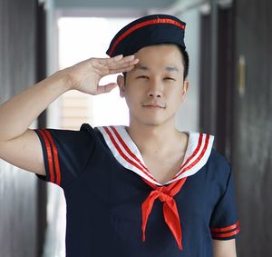 Portrait of man saluting while wearing sailor suit at home