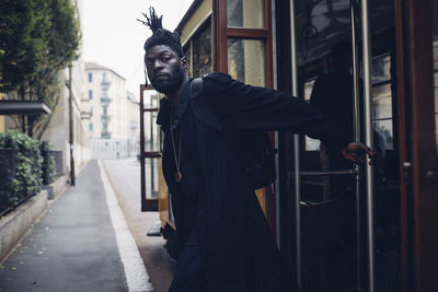 Man looking away while hanging on tram railing