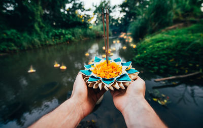 Midsection of person holding umbrella on water