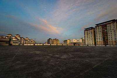 Buildings by road against sky at sunset