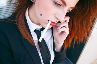Close-up of businesswoman smoking while talking on smart phone