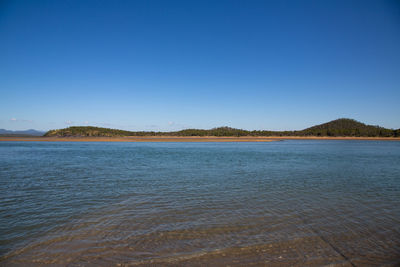 Scenic view of lake against clear blue sky