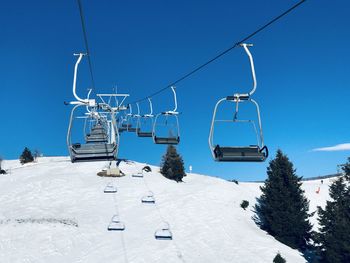 Low angle view of snow covered mountain against clear sky with chair lift for skiing 