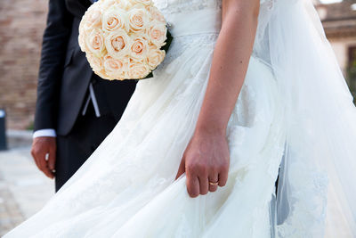 Low section of couple holding bouquet