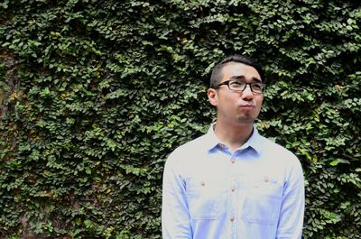 Man in eyeglasses making face against plants