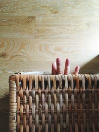 Cropped hand of baby in wicker basket at home