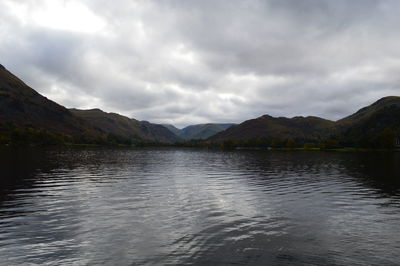 Scenic view of lake and mountains against cloudy sky