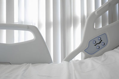 Close-up of white bed against curtain at hospital