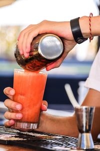 Cropped image of bartender pouring cocktail in glass