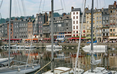 Boats moored at harbor against buildings in city
