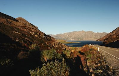 Scenic view of sea and mountains against clear blue sky