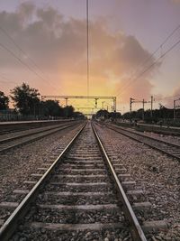 Railroad tracks against sky during sunset