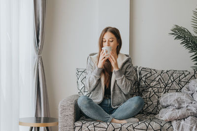 Young woman sitting on sofa at home