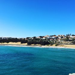 Sea by residential district against clear sky