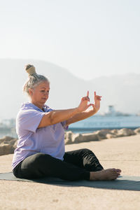 Side view of woman sitting on sand at beach