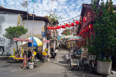 Cars on street by buildings in city against sky