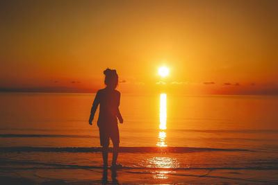 Silhouette woman standing at beach during sunset