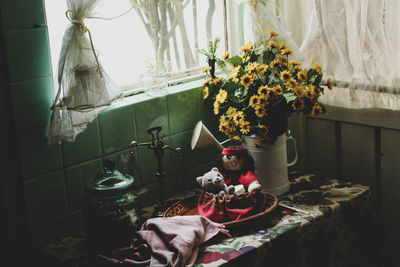 Flower vase with stuffed toy on table at home