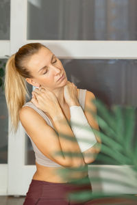 Beautiful young woman practicing sports at home. sporty girl exercising fitness stretches back 