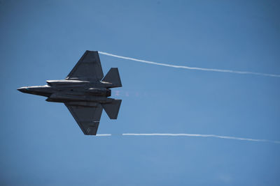 Low angle view of airplane flying against blue sky