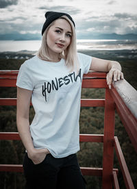 Young woman standing against railing