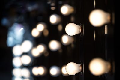 Close-up of illuminated light bulbs on dressing table at backstage