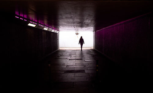 Silhouette man standing in illuminated corridor