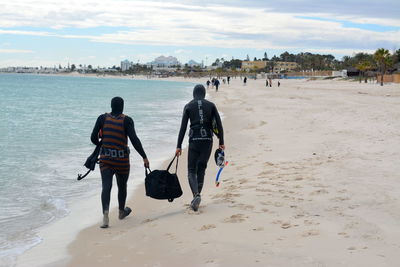 Rear view of people walking on beach