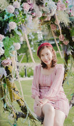 Portrait of a smiling young woman sitting by plants