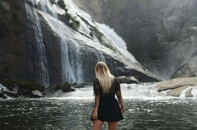 Rear view of woman standing by waterfall