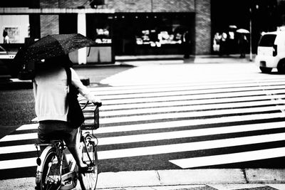 Rear view of woman with bicycle walking on road