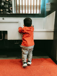 Rear view of boy standing on washbowl