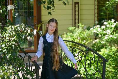 Portrait of smiling young woman standing against plants