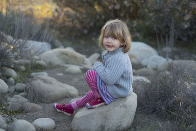 Portrait of girl sitting on rock