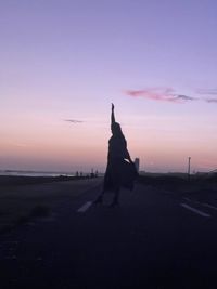 Silhouette people on beach against sky during sunset