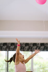 Little girl playing with a pink balloon at home