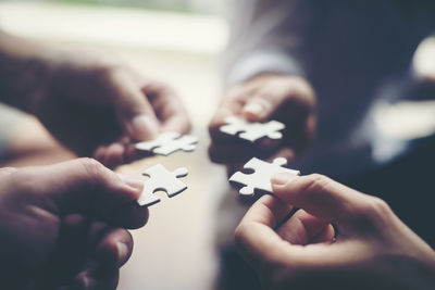 High angle view of people holding jigsaw piece on table