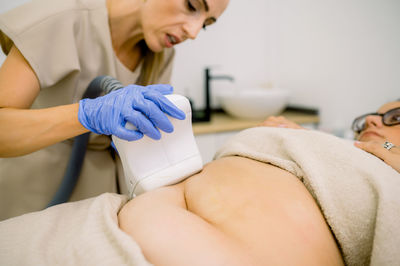 Midsection of doctor examining patient in hospital