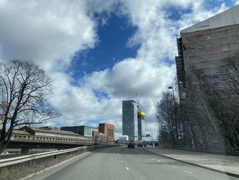 Road by buildings in city against sky