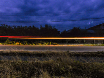 Light trails on field against sky at sunset