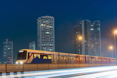 Train against buildings and sky at night