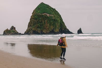 Rear view of woman standing at beach
