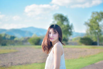 Side view of young woman looking away against sky